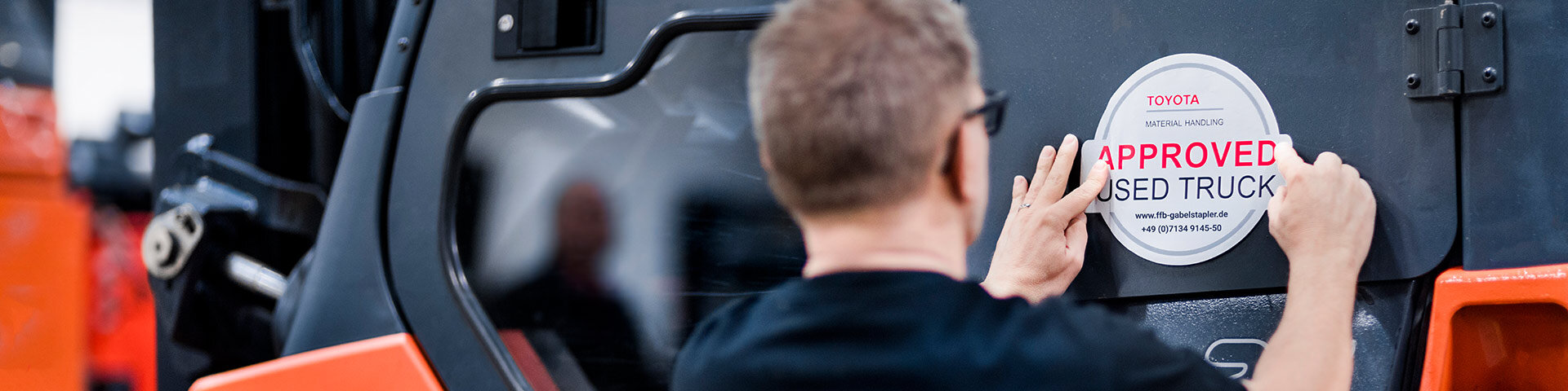 Toyota Mitarbeiter klebt einen Qualitöts-Aufkleber auf einen Gabelstapler
